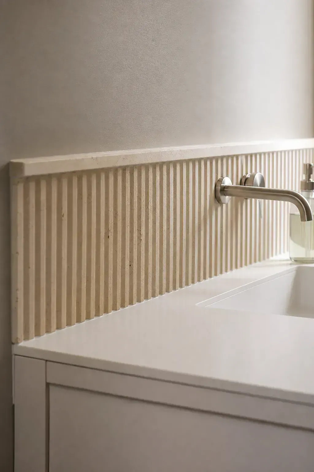 White bathroom vanity with fluted warm stone backsplash