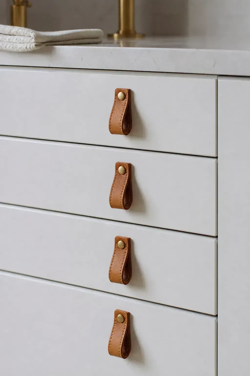 White vanity drawers with warm leather pulls
