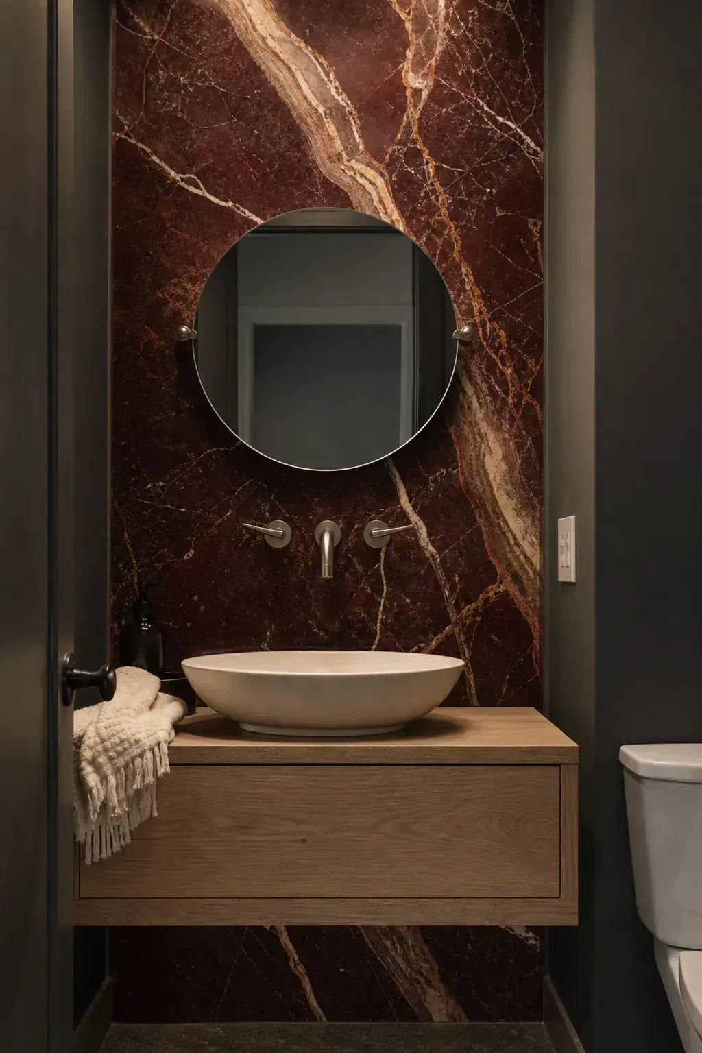 Dramatic richly veined stone slab backsplash in a moody powder room