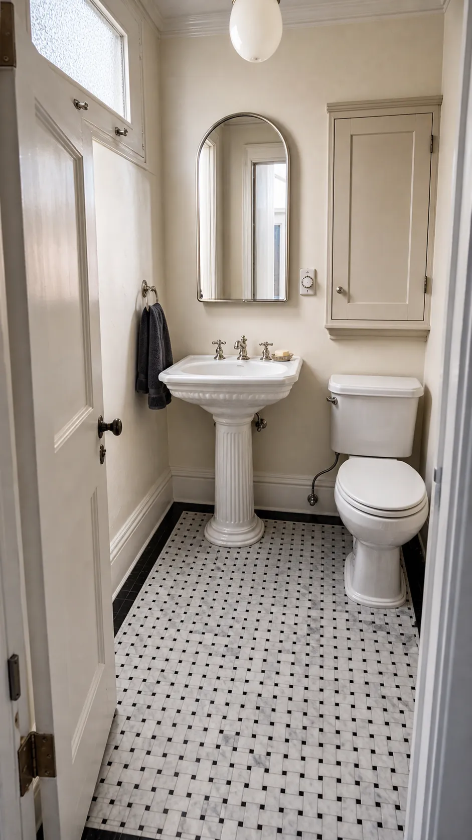 Pedestal sink grounded by a marble mosaic floor in an elegant half bath