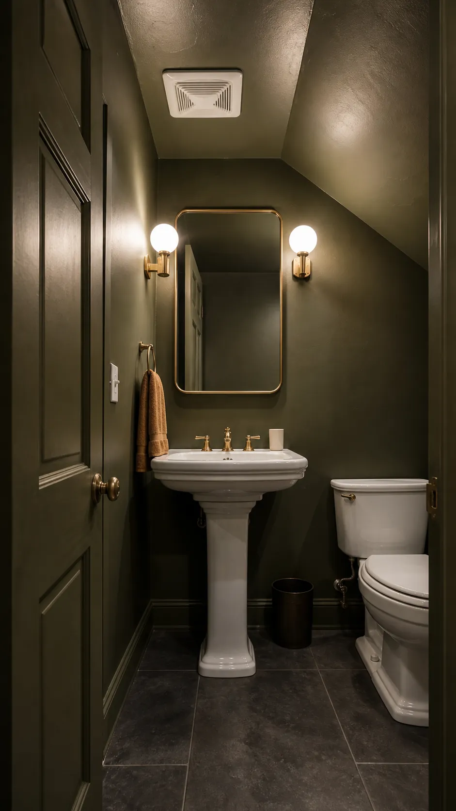 White pedestal sink against a deep moody green wall in a half bathroom