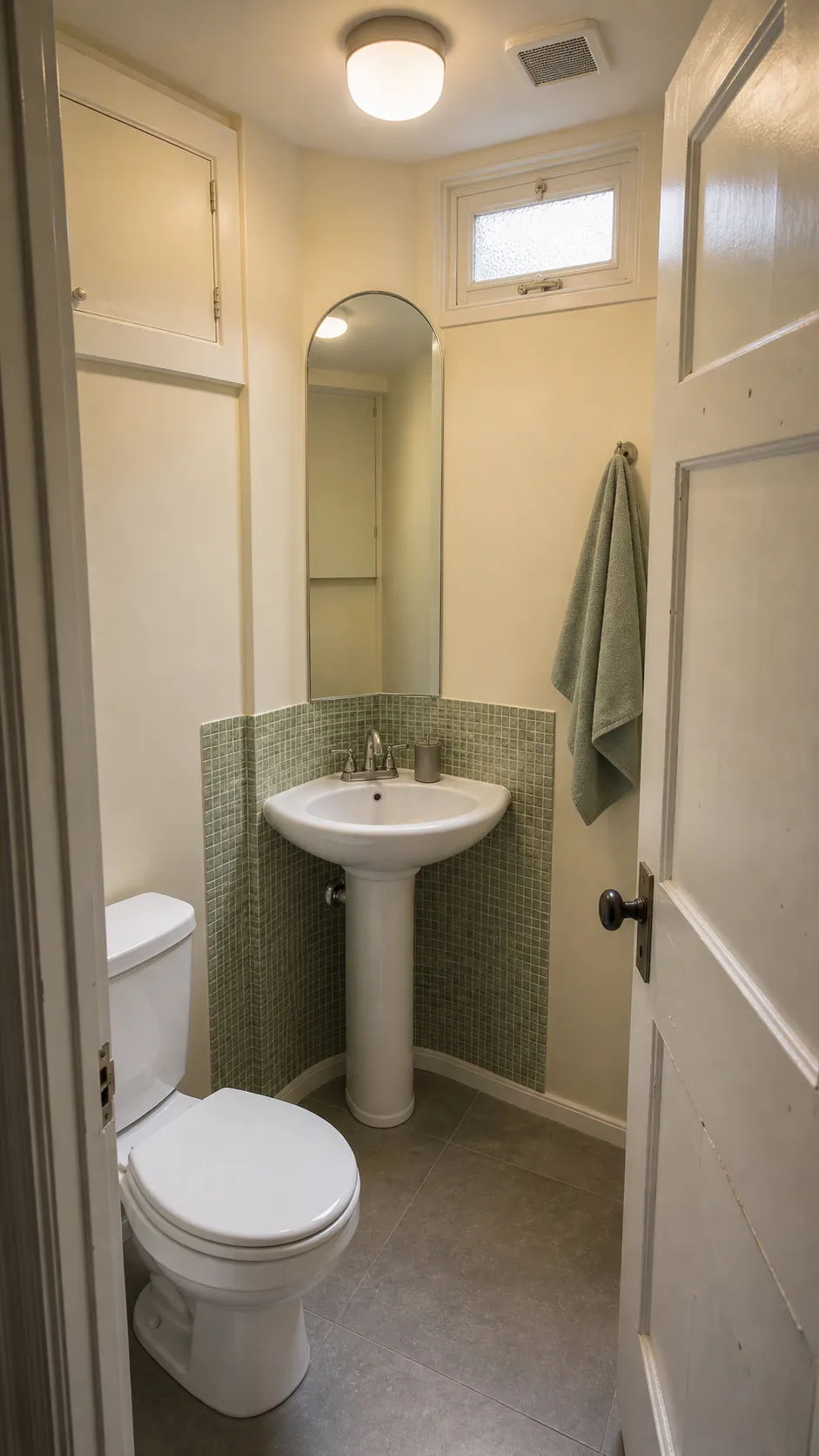 Compact pedestal sink fitted into a softened corner of a tiny half bathroom