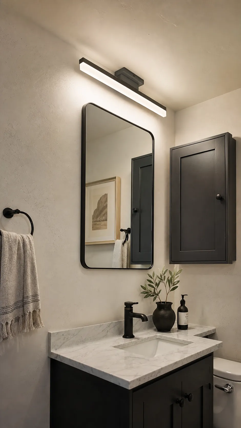Slim vanity light mounted above a mirror in a compact bathroom