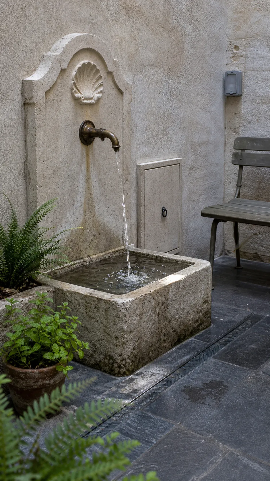 Small stone wall fountain in an intimate French patio