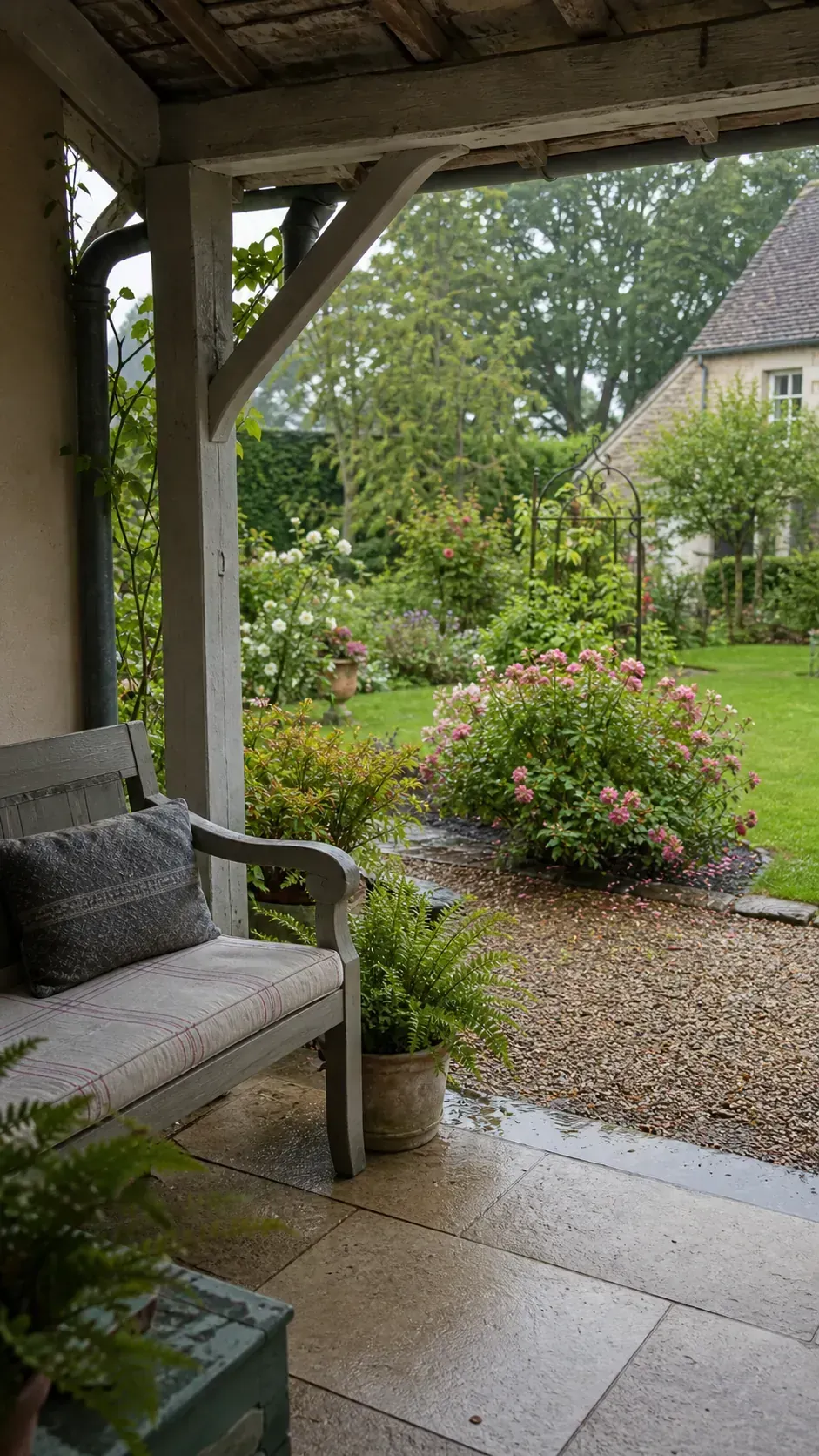 Covered French cottage patio nook overlooking a rain-washed garden