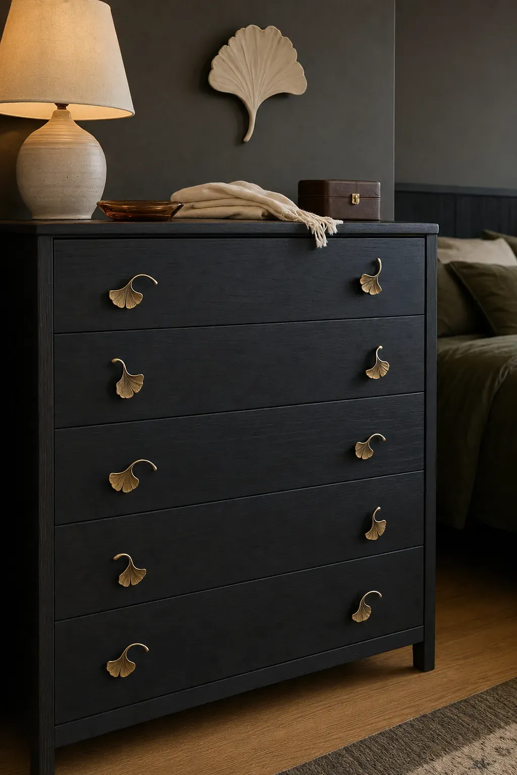 Aged brass leaf-shaped hardware on a dark bedroom dresser