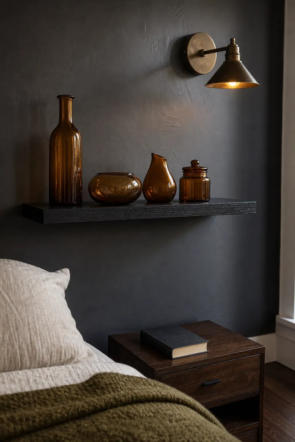 Amber glass vessels glowing on a black bedroom shelf