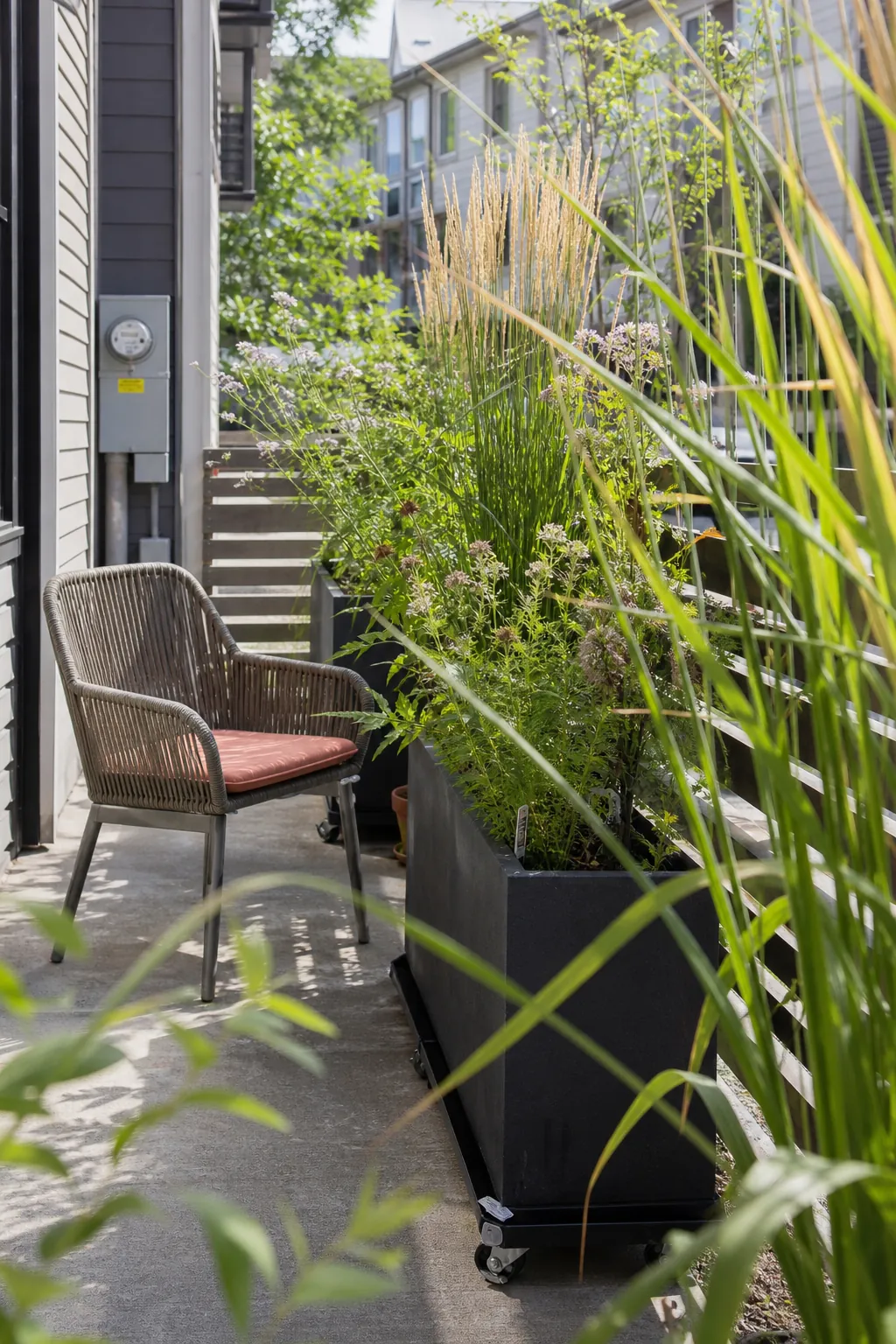 Townhome patio screened by tall movable planters with upright grasses