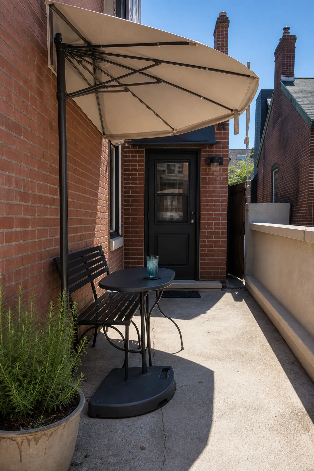 Small townhouse patio shaded by a space-saving half umbrella