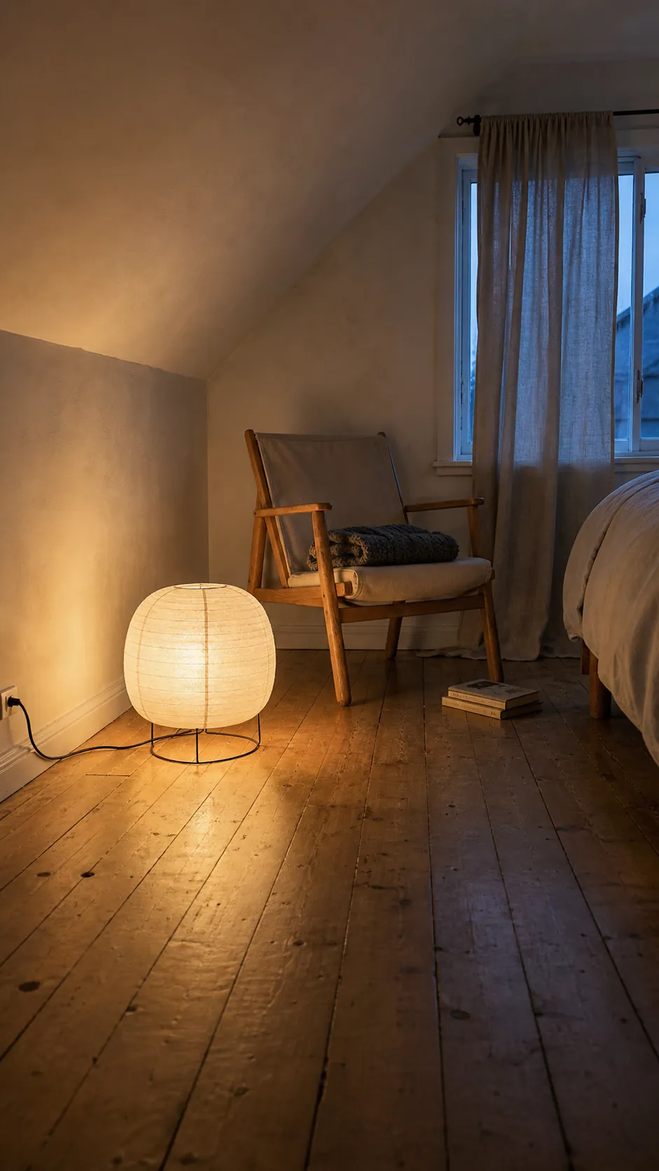 Low rice-paper lantern glowing beside a bedroom chair