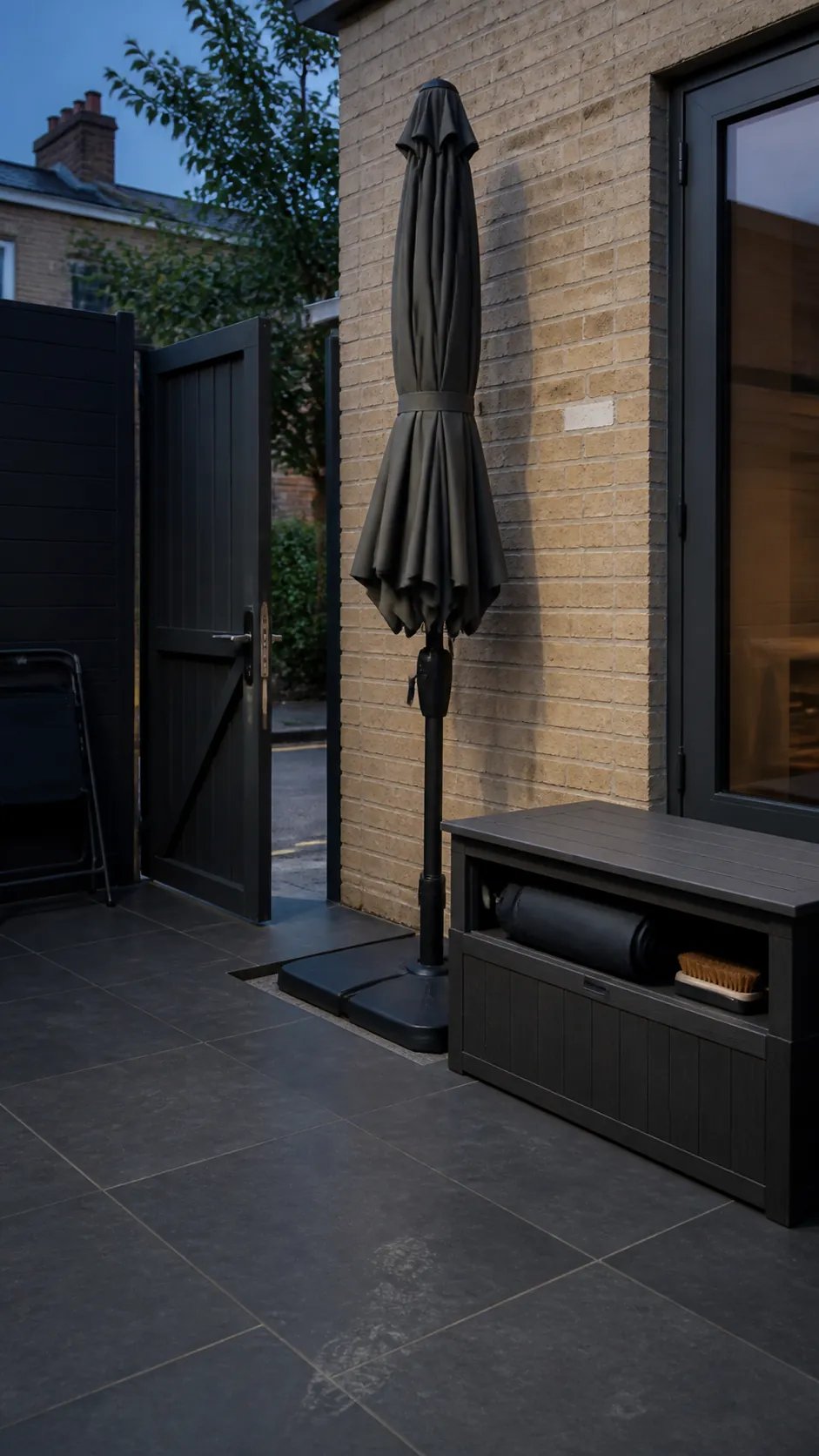Closed and strapped patio umbrella parked safely beside a storage bench