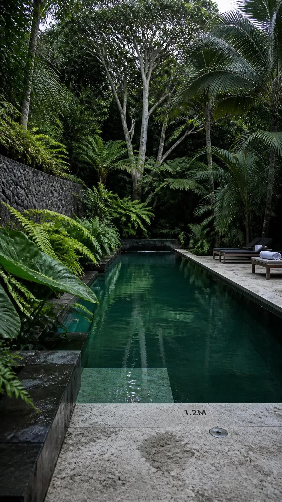 Dark stone tropical pool with clear emerald water and lush foliage