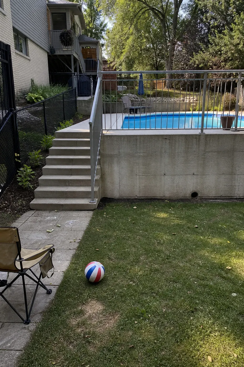 Open lower play terrace below a swimming pool in a split-level backyard