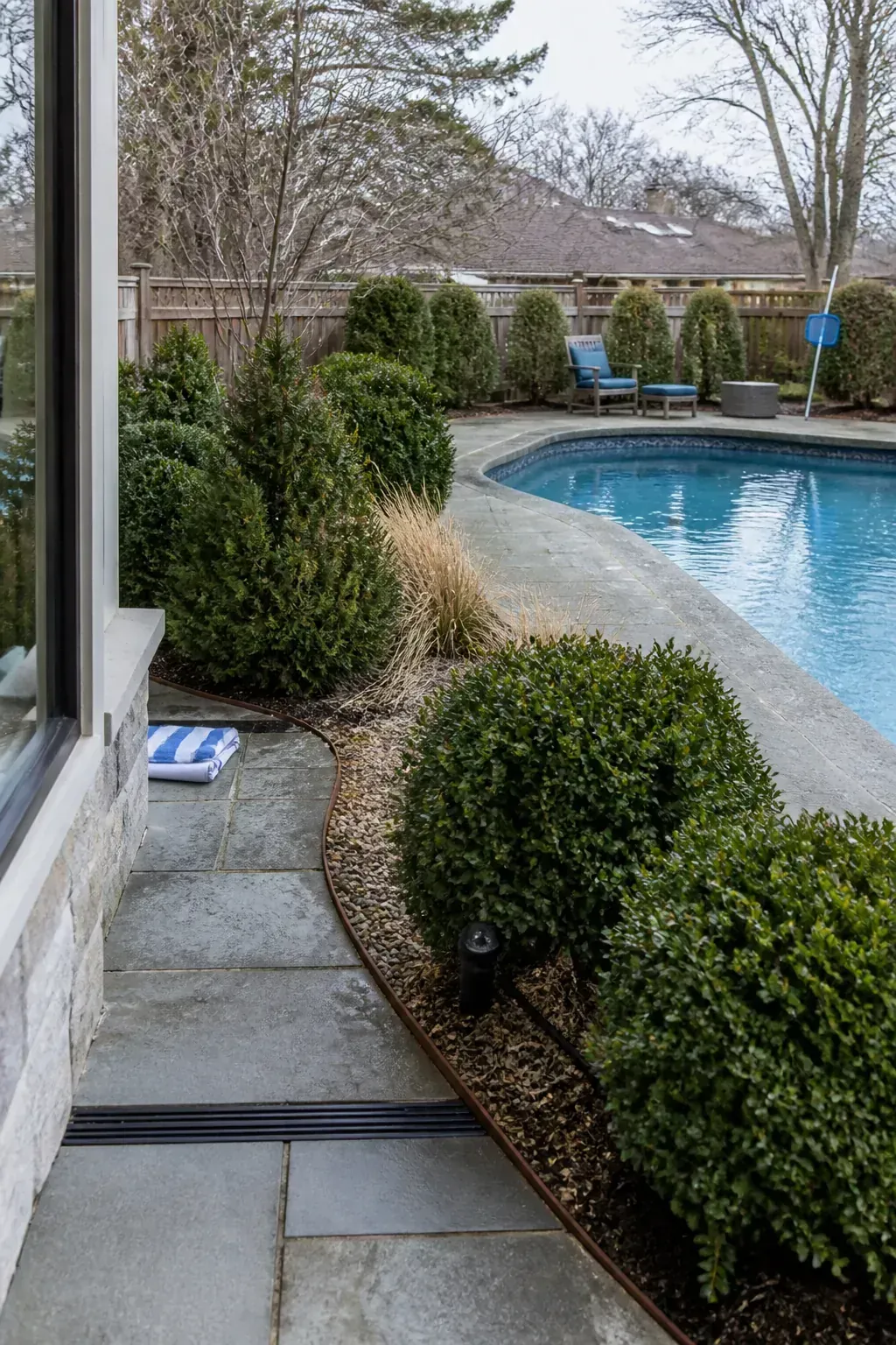 Evergreen shrubs providing year-round pool garden structure