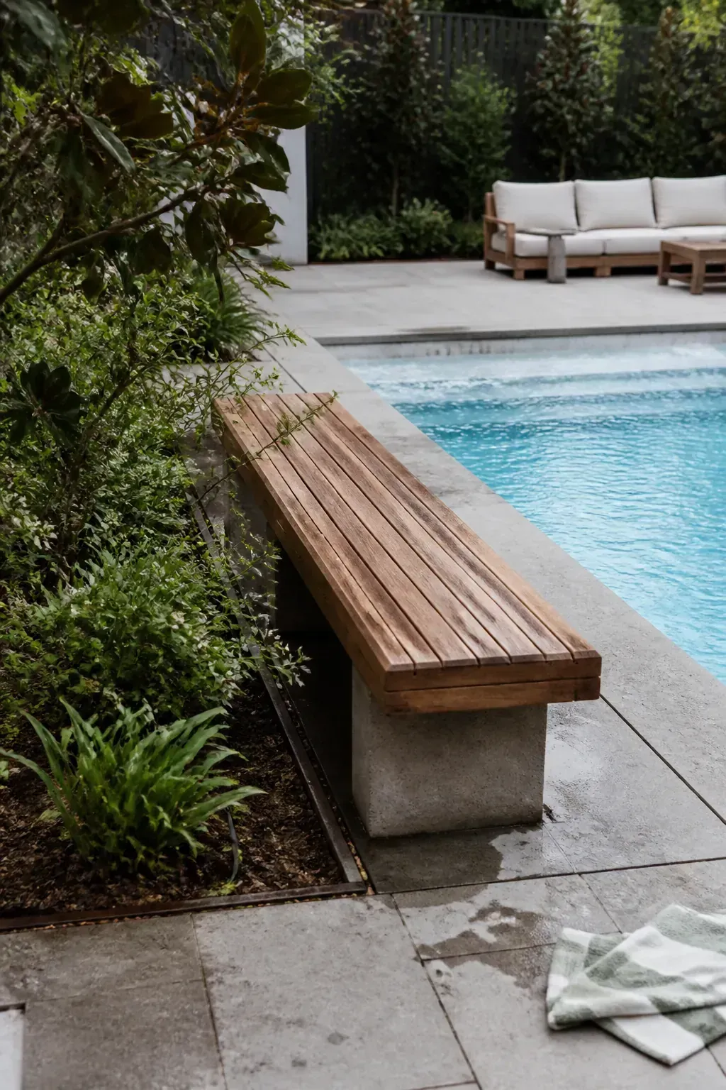 Simple timber bench bridging pool paving and a planted bed