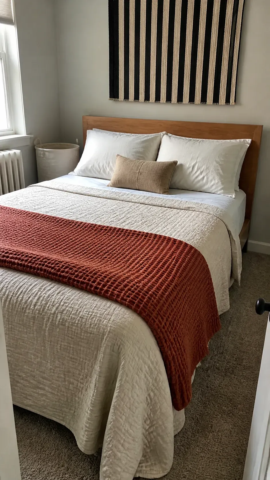 Layered neutral bedding adding texture to a compact apartment bedroom
