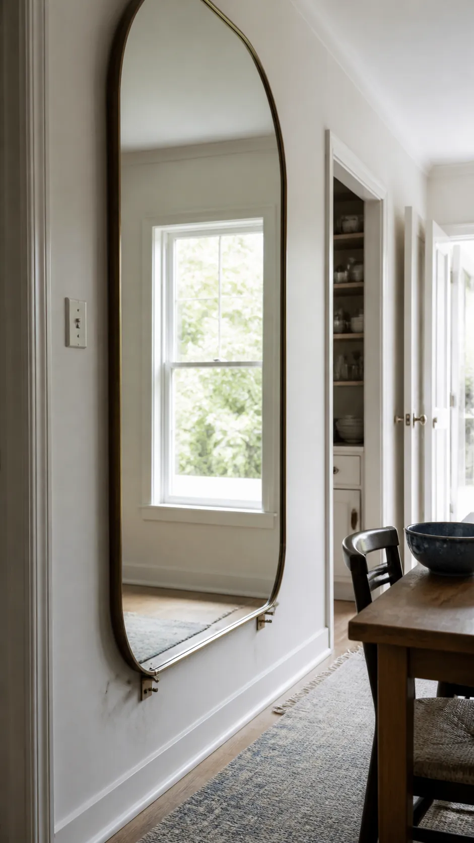 Oversized mirror reflecting daylight across a compact room