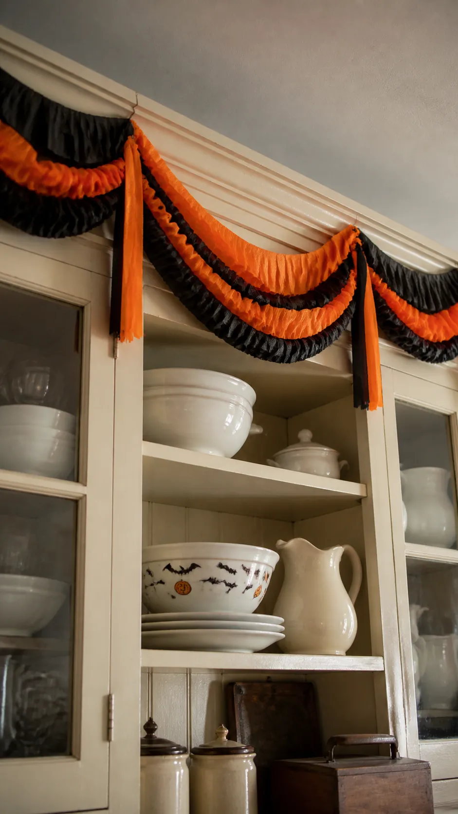 Orange and black crepe paper festoon above a kitchen hutch