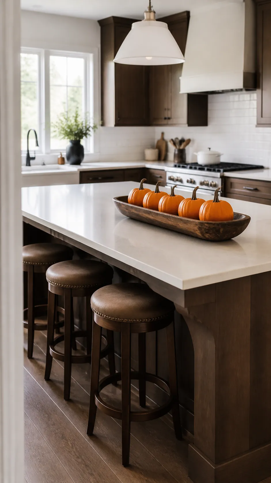 Wooden bowl of pumpkins on a clear Halloween kitchen island
