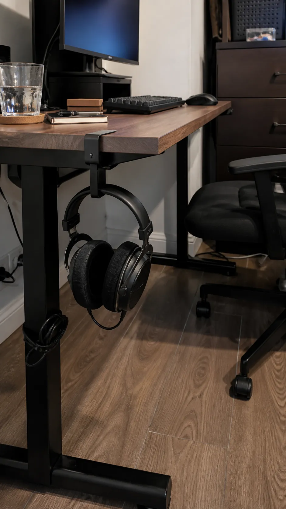 Headphones stored on a hook beneath a tidy small desk