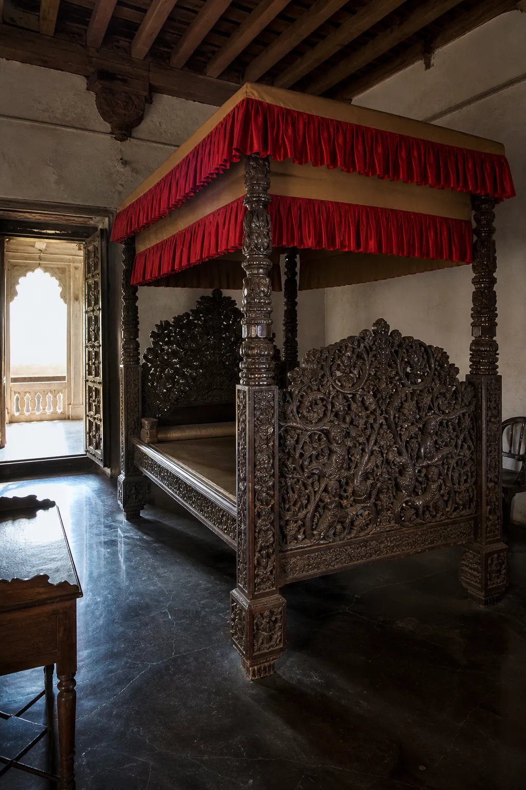 Traditional Indian canopy bed with intricately carved dark wood posts and decorative panels