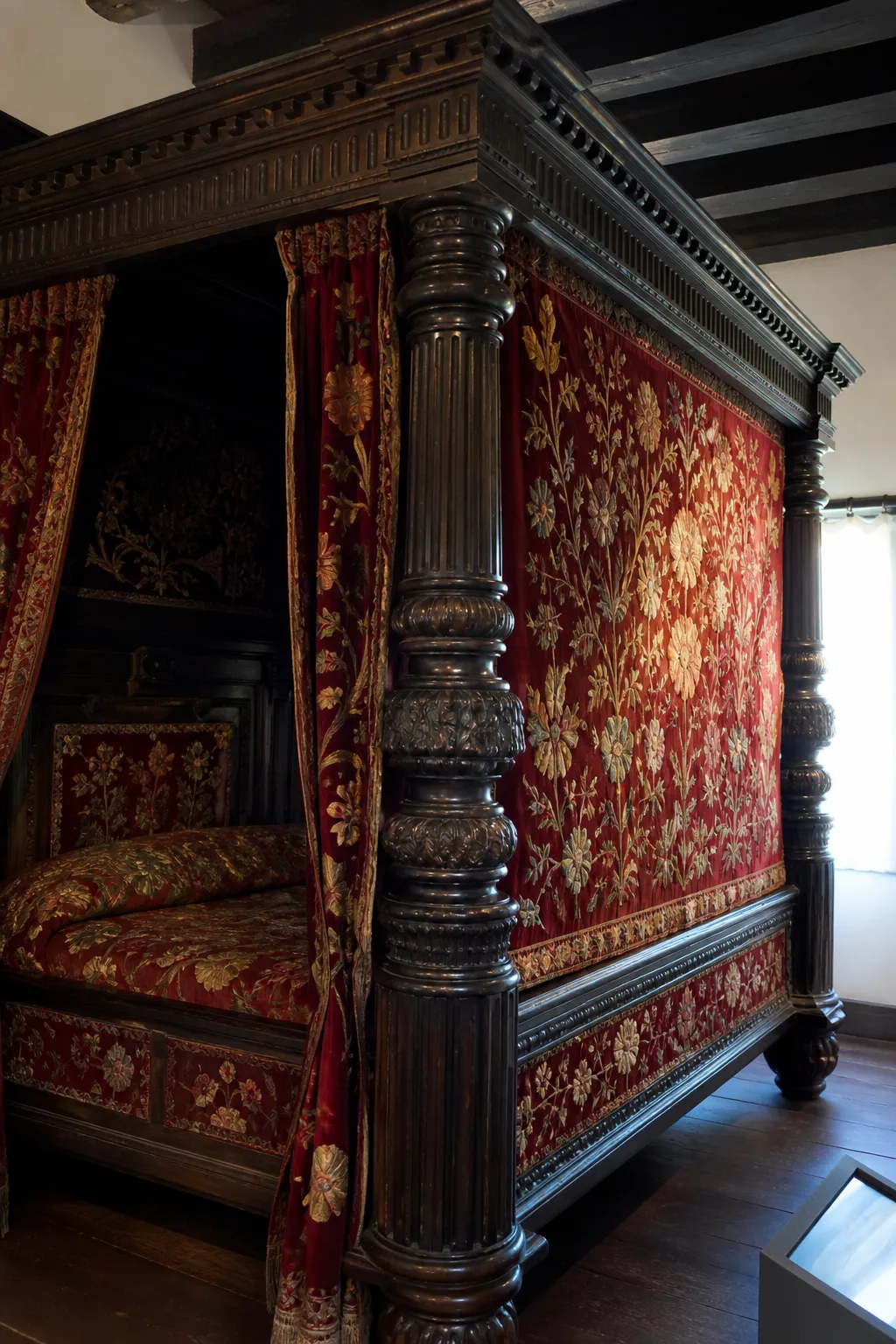 Dark wood canopy bed styled with colorful floral embroidered bedding