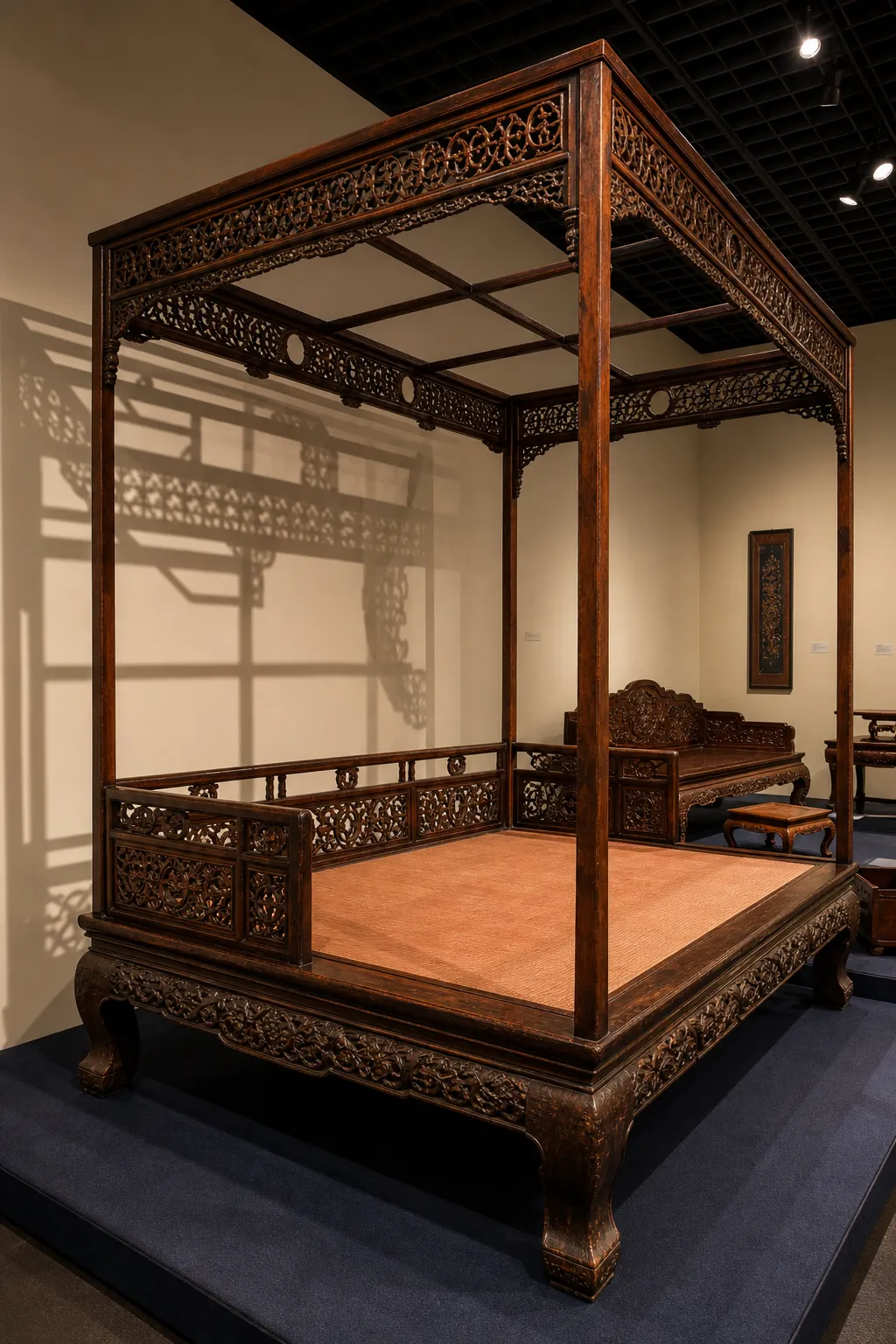 Chinese four-poster bed featuring sculptural dark wood posts and carved panels