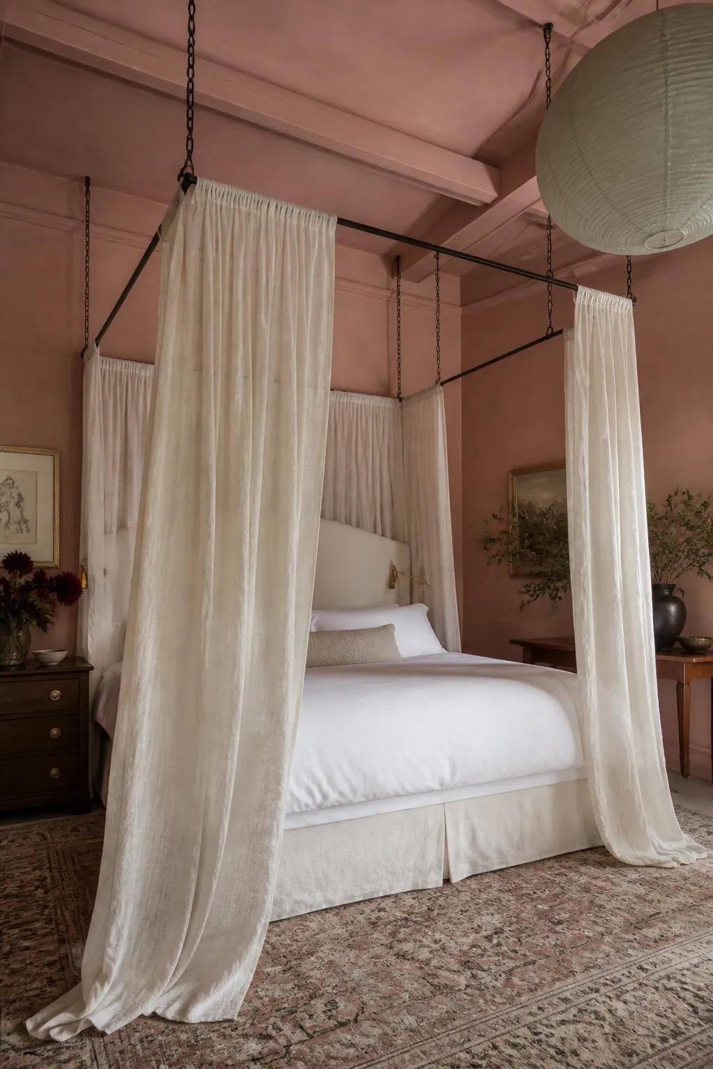 White bed beneath suspended floor-length canopy fabric cascading from the ceiling