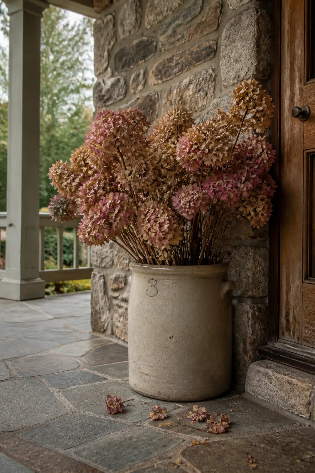 Dried hydrangeas arranged in a heavy ceramic porch crock