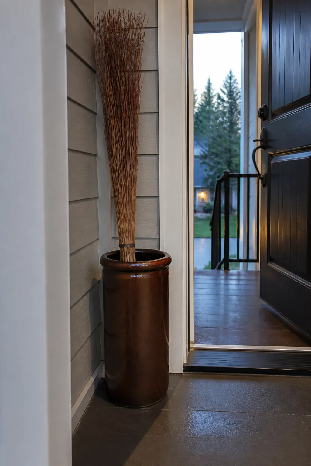 Cinnamon broom standing securely in a weighted porch crock