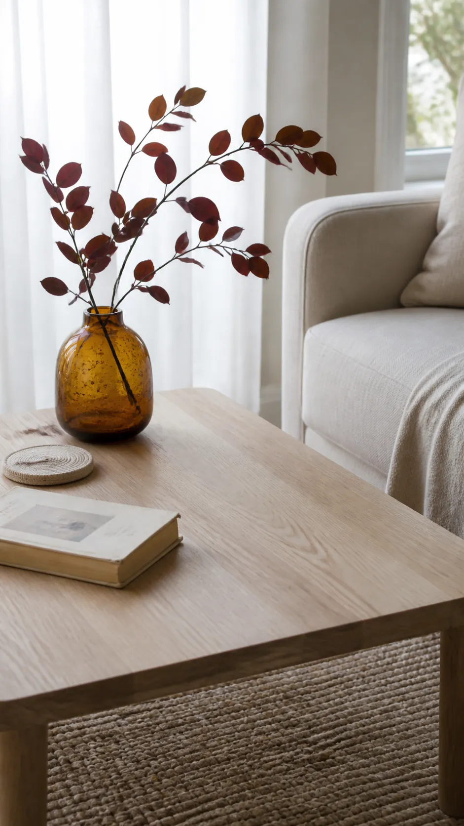 Amber glass vase with autumn leaves on a coffee table