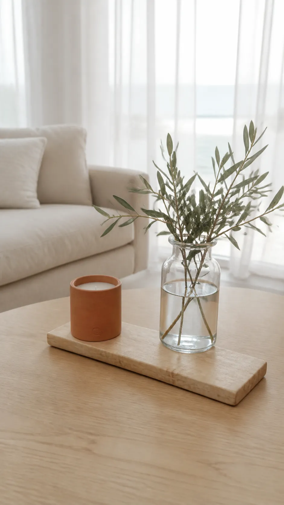 Terracotta candle with olive branches on a pale wood board