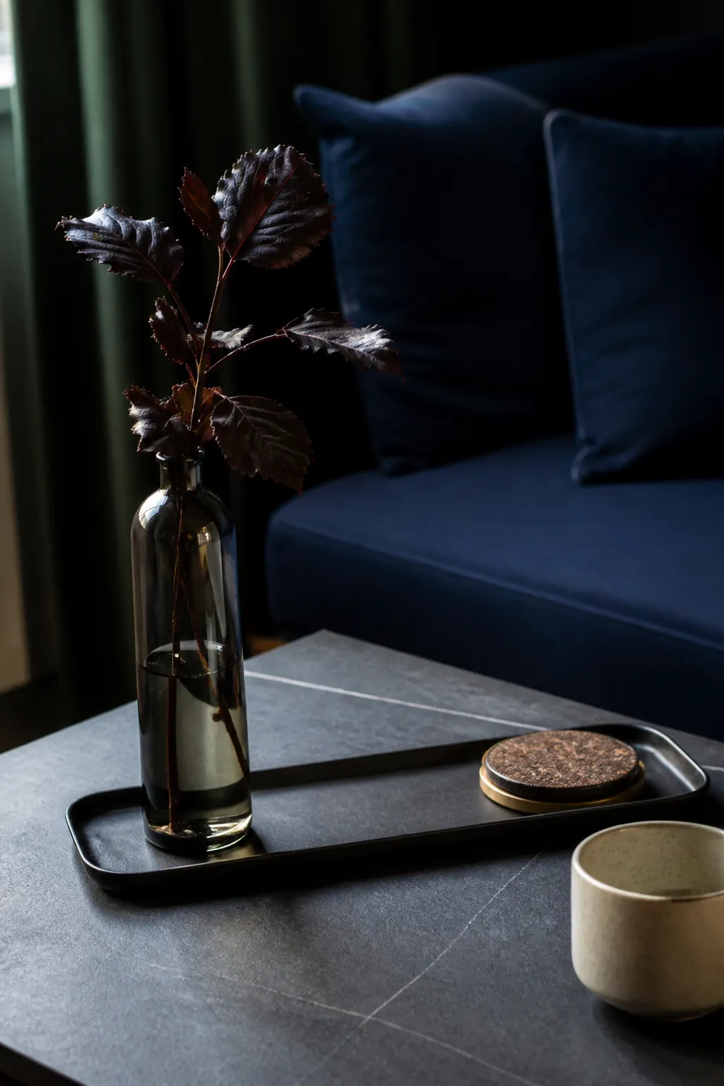Smoked glass bottle and burgundy stems on a charcoal tray