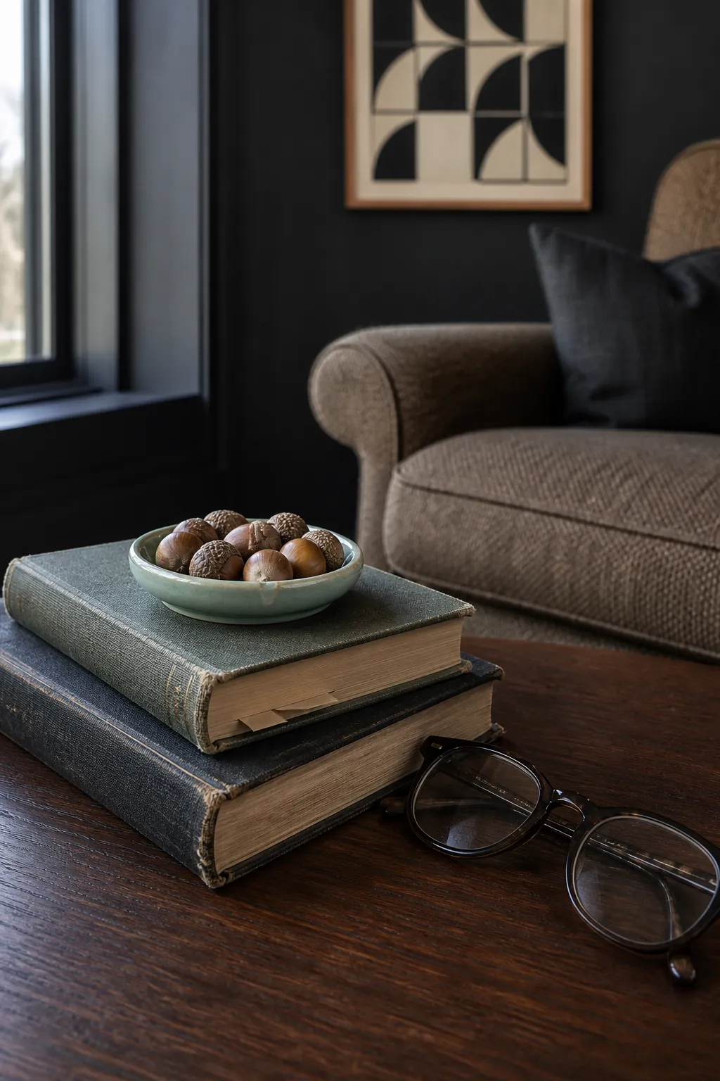 Personal books topped with a tiny acorn dish on a coffee table