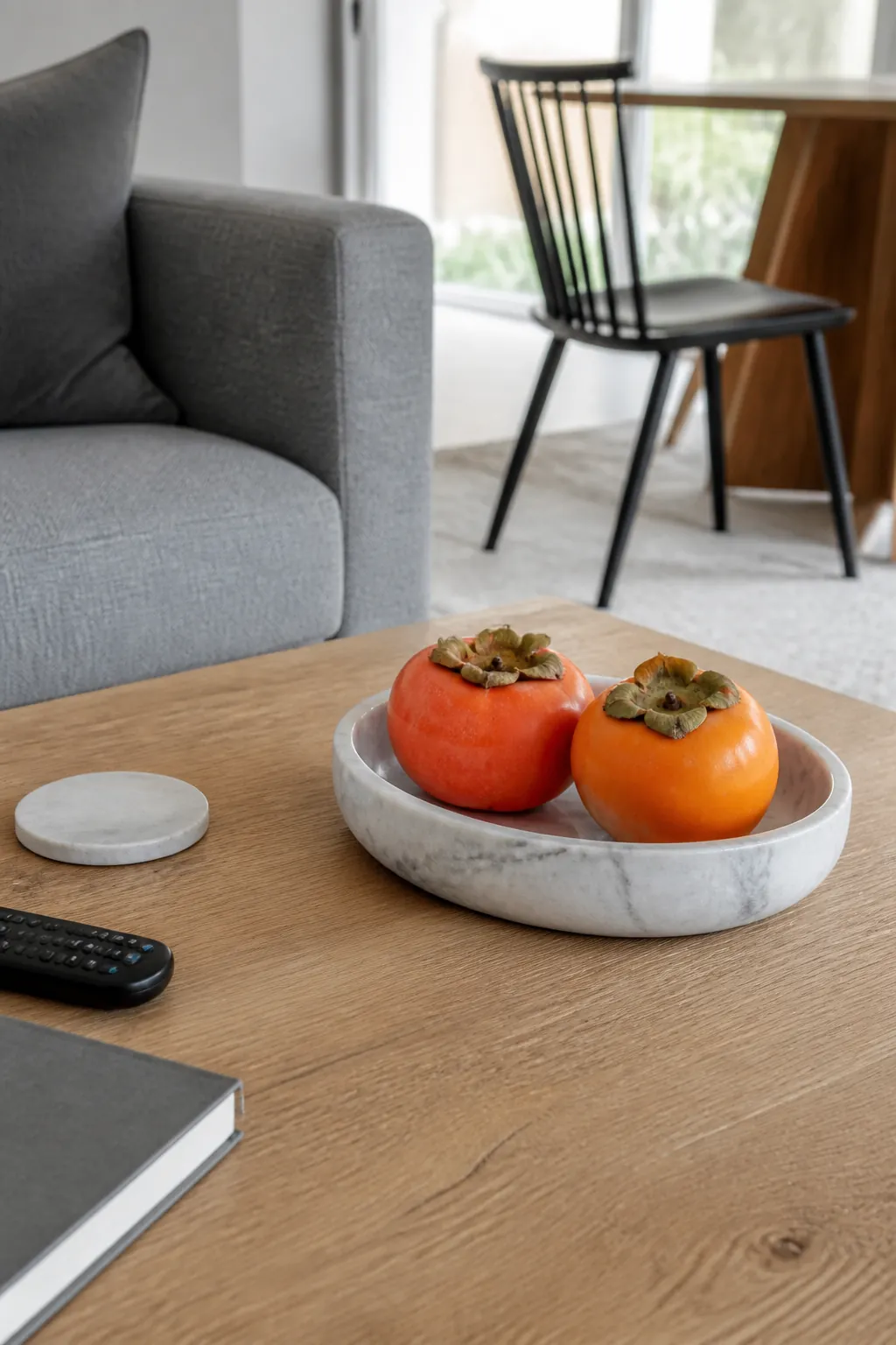 Persimmons in a veined marble dish for colorful fall coffee table decor