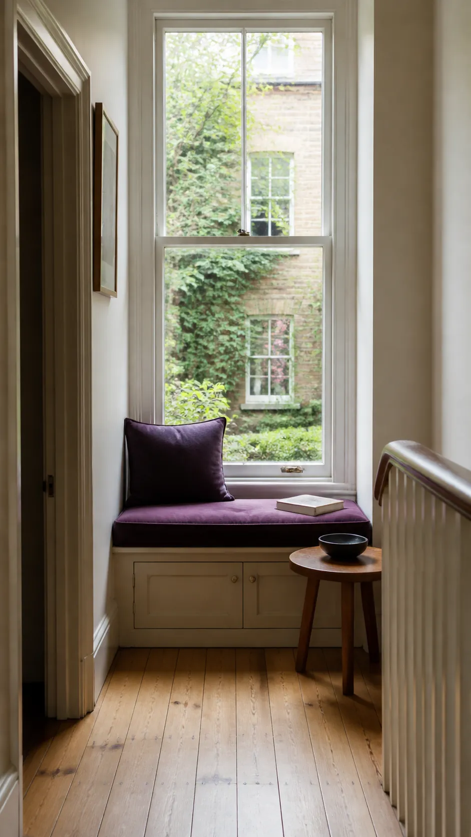 Comfortable window reading seat with plum cushions and a small side table