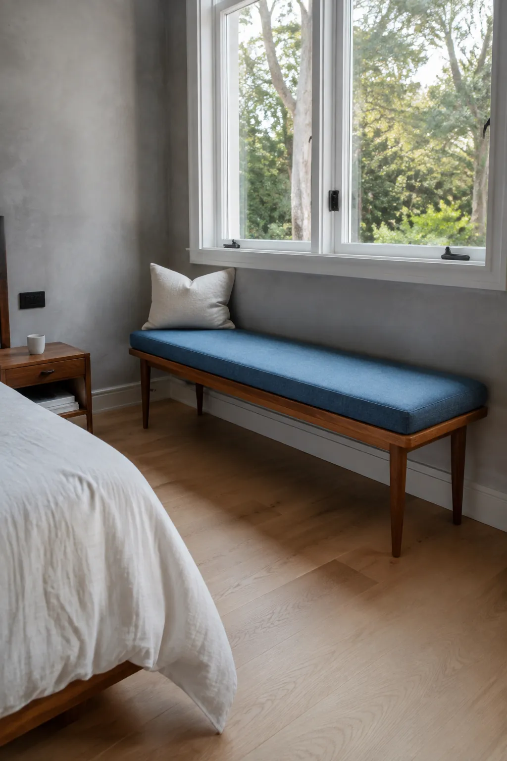 Bedroom window bench with a blue cushion and clear space beside the bed