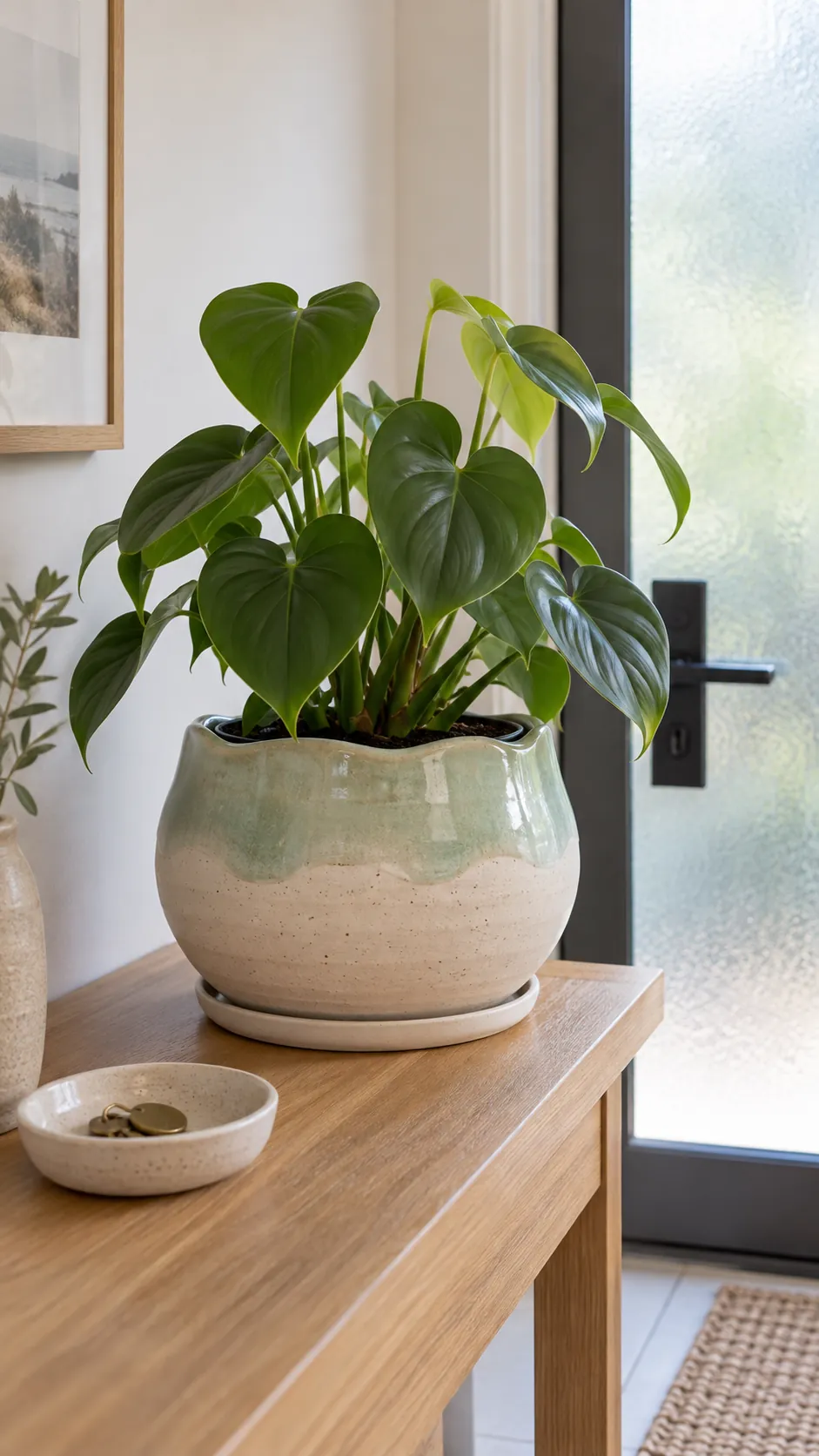 Handmade ceramic planter with seafoam glaze and a philodendron near a bright entry door