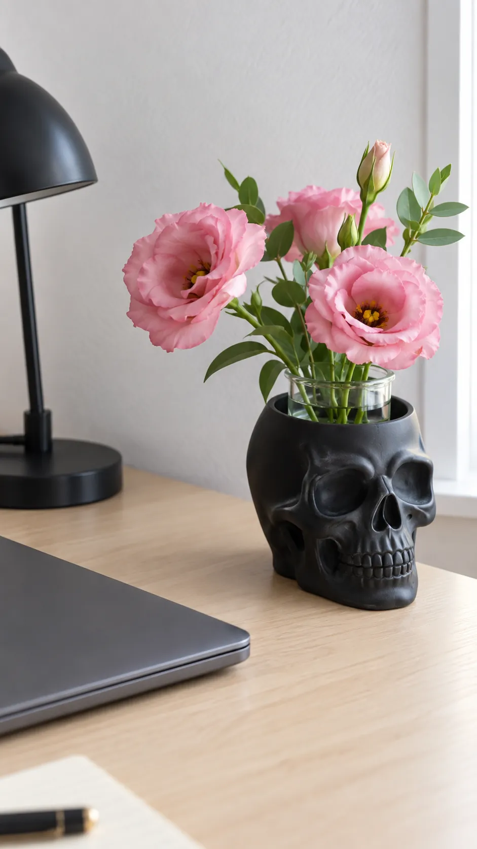 A skull vase with fresh pink flowers in black and pink Halloween decor