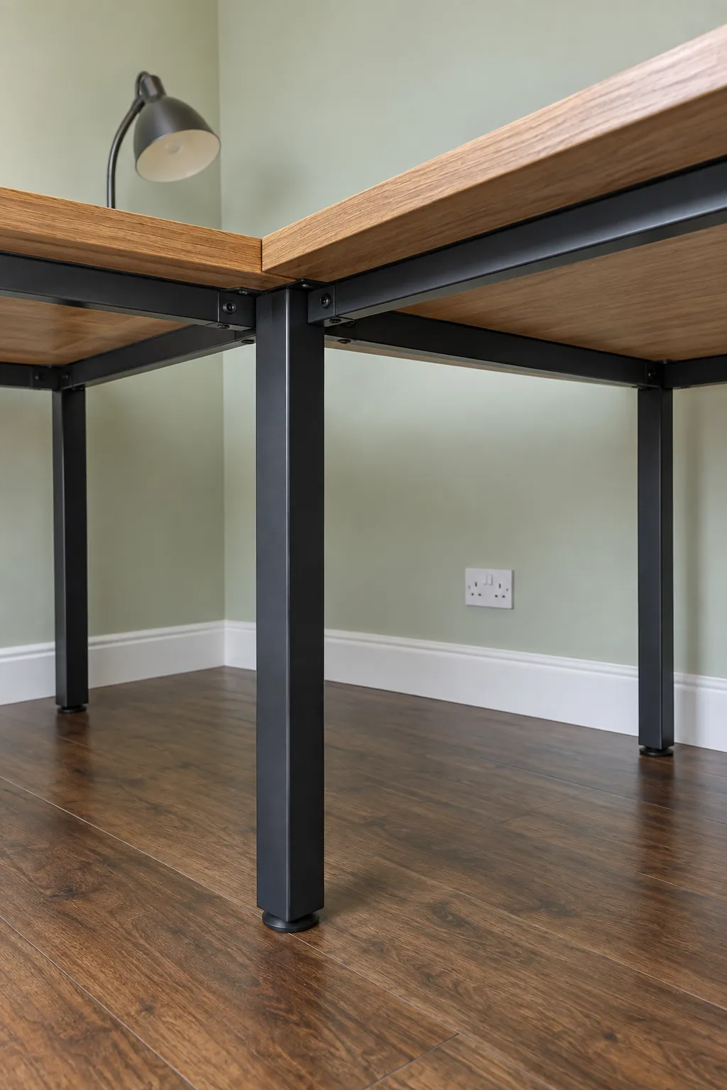 Separate supports beneath two meeting corner desk surfaces