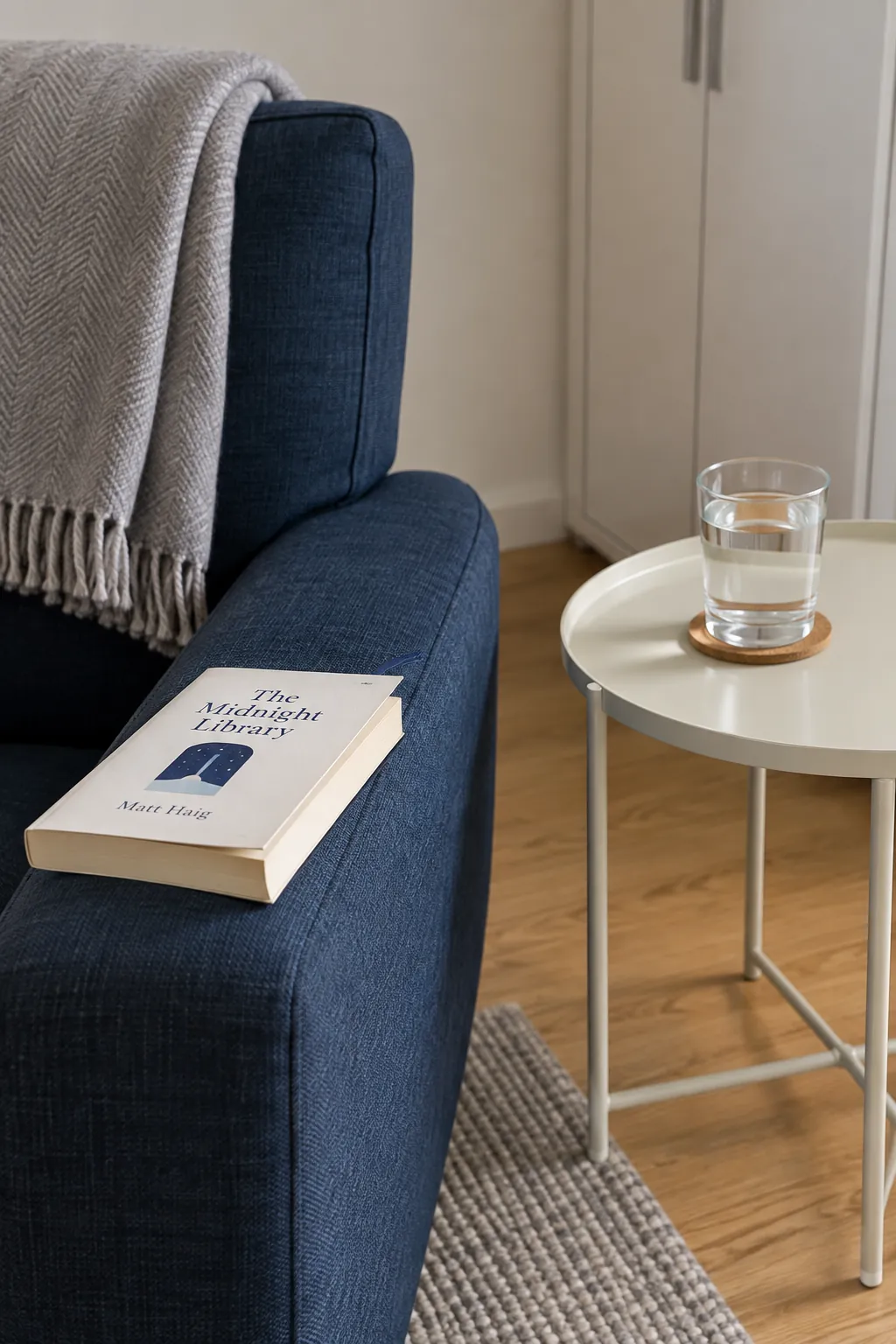 A current book and separated drink beside a comfortable seat