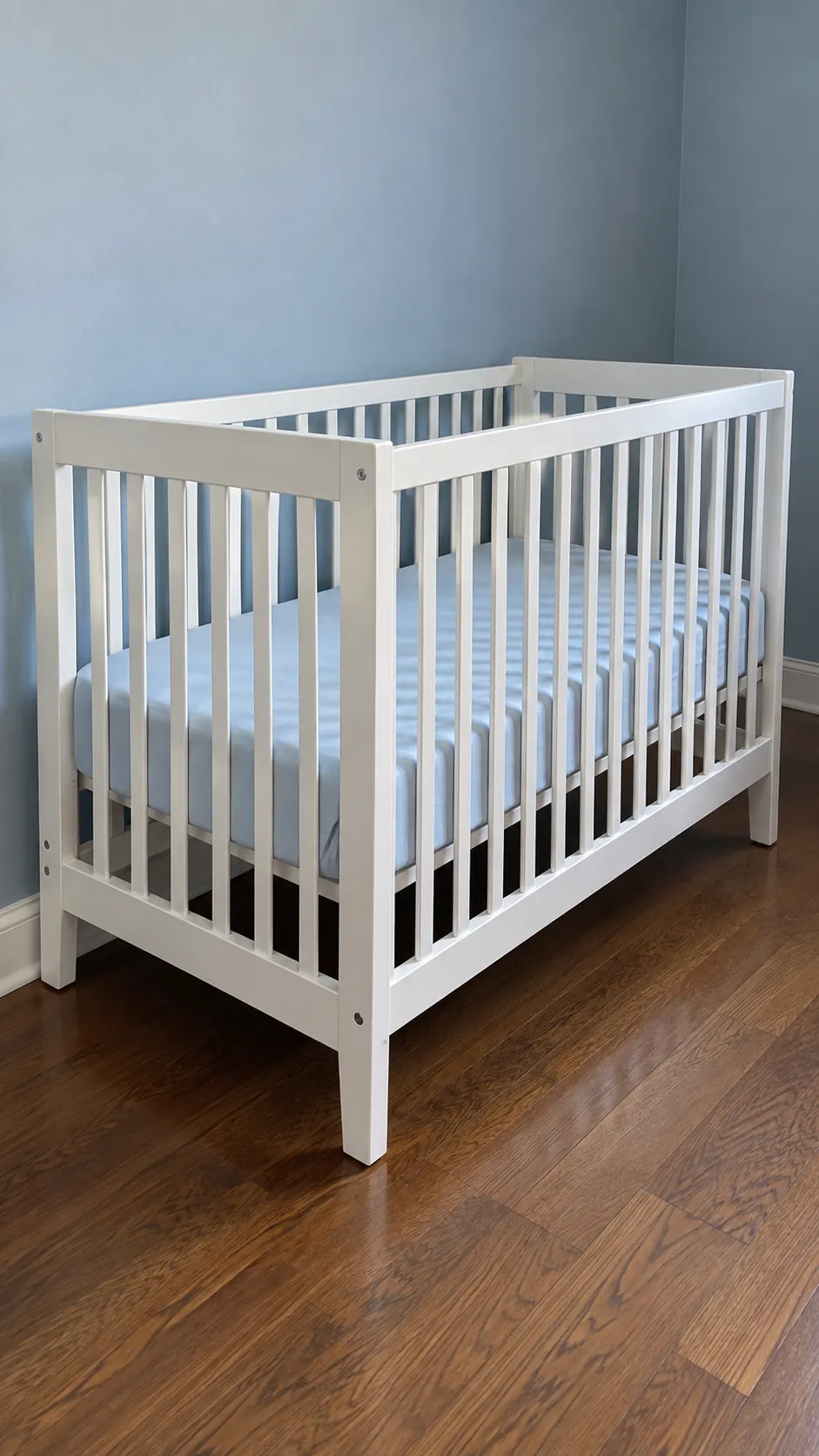 Bare crib beside a clear nursery wall