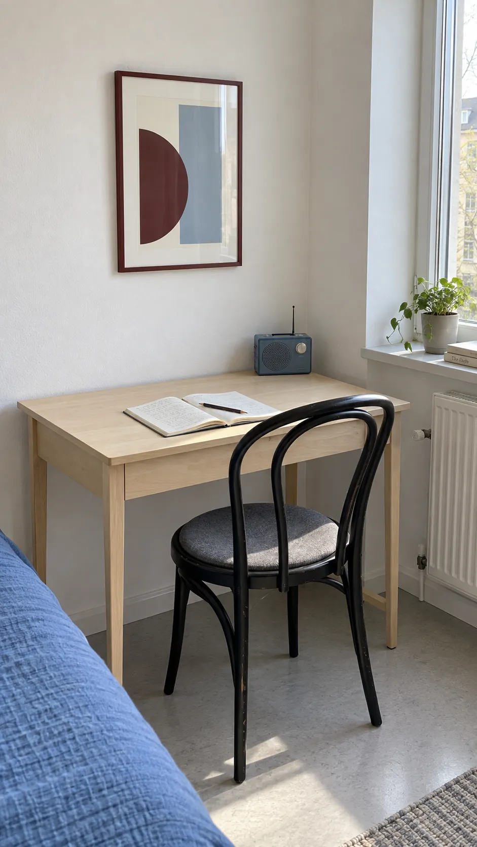 Small pale wood bedroom desk with a geometric print, radio, and clear working space