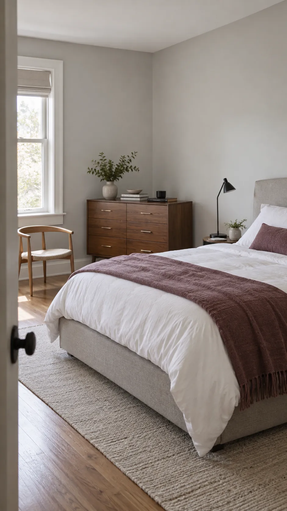 Retro modern bedroom pairing an upholstered bed with walnut storage and plum textiles