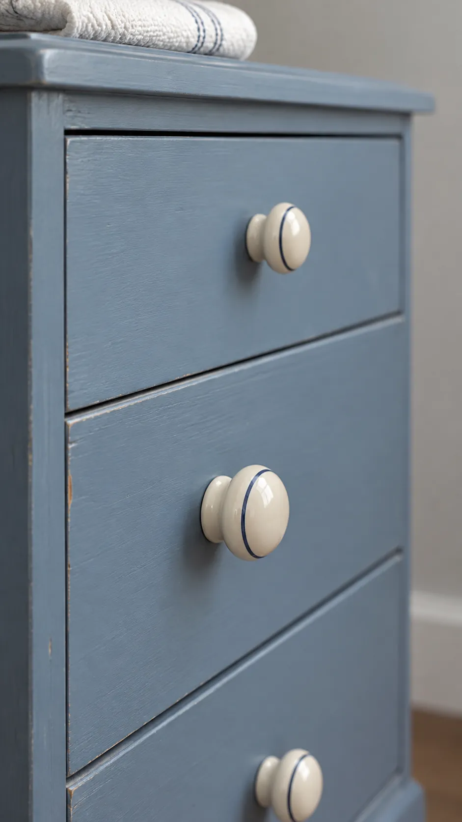 Cream ceramic knobs on a blue painted bedroom cabinet