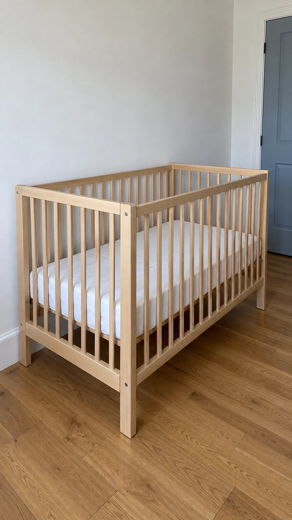 Empty crib with fitted sheet away from windows and cords