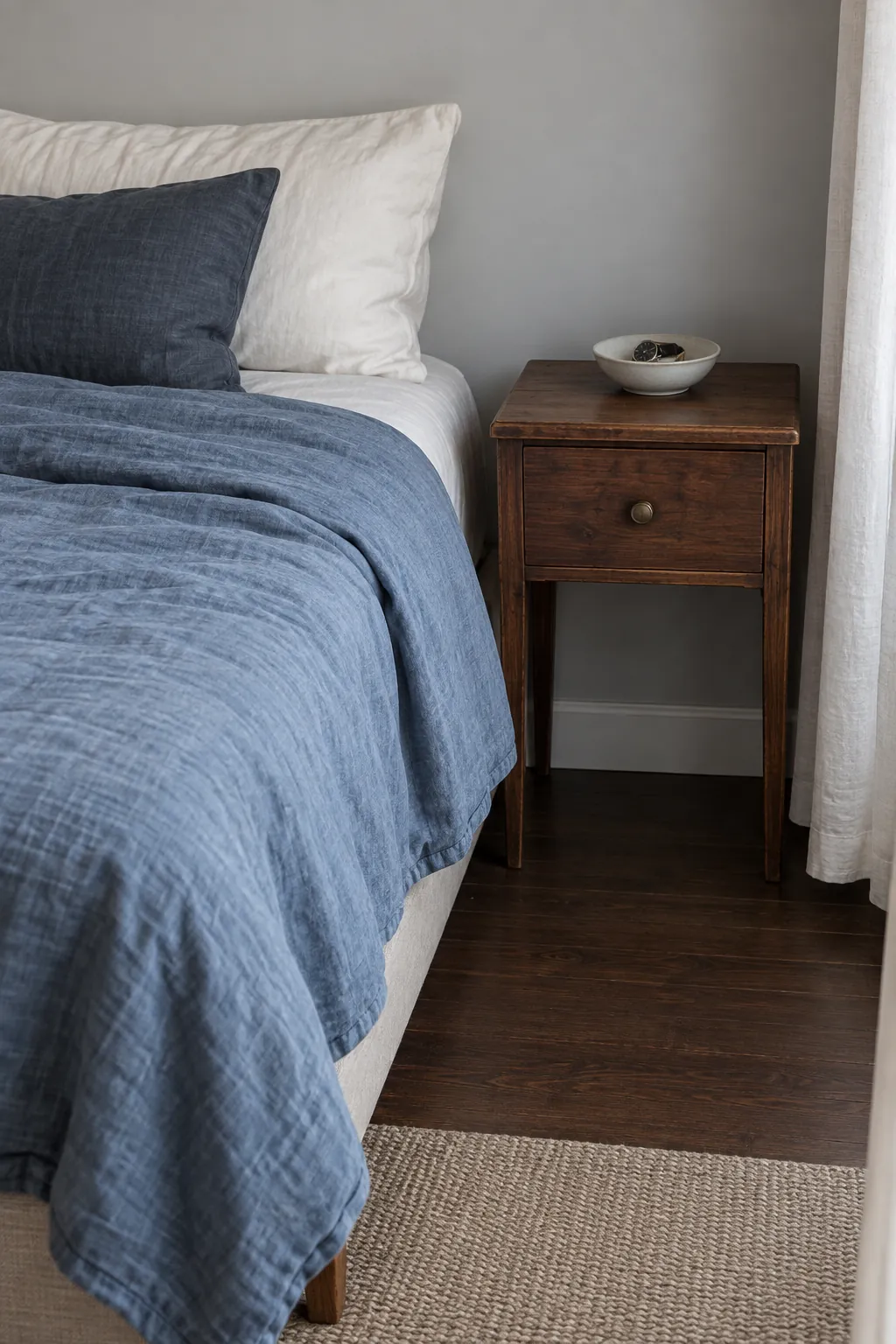 Muted blue bedding and warm wood create a coherent small apartment color palette
