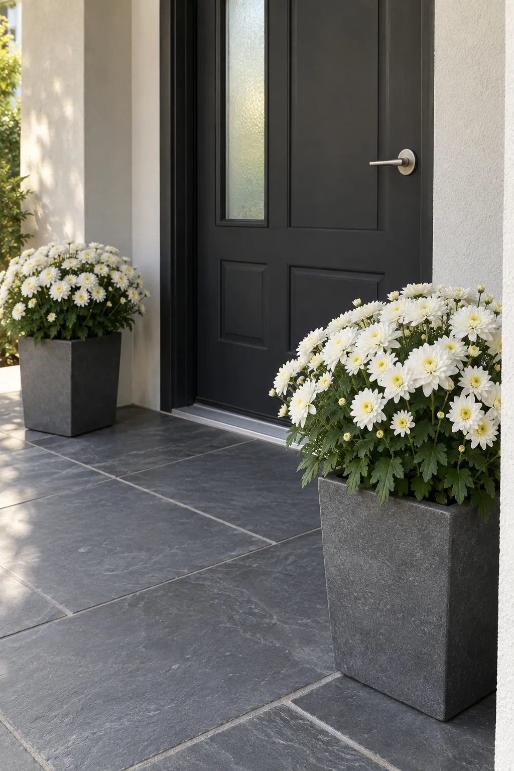 White flowers around a dark front door with fall mums on a front porch