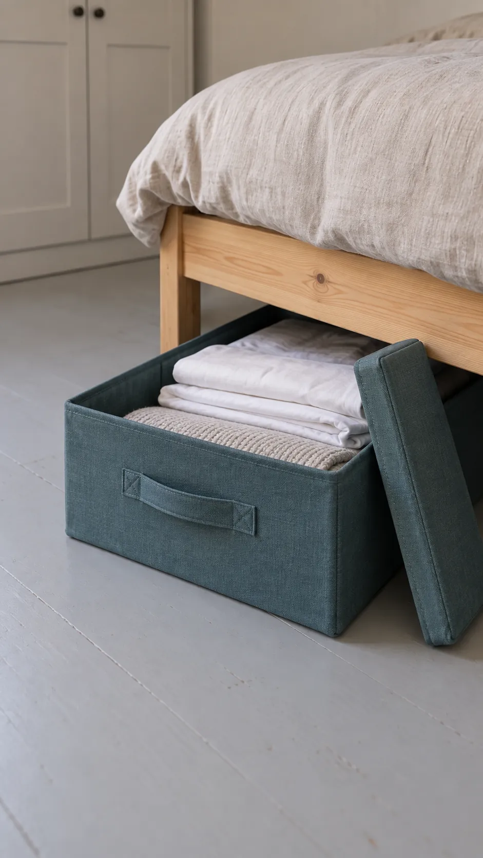 A practical close interior photograph of accessible storage beneath a simple studio bed