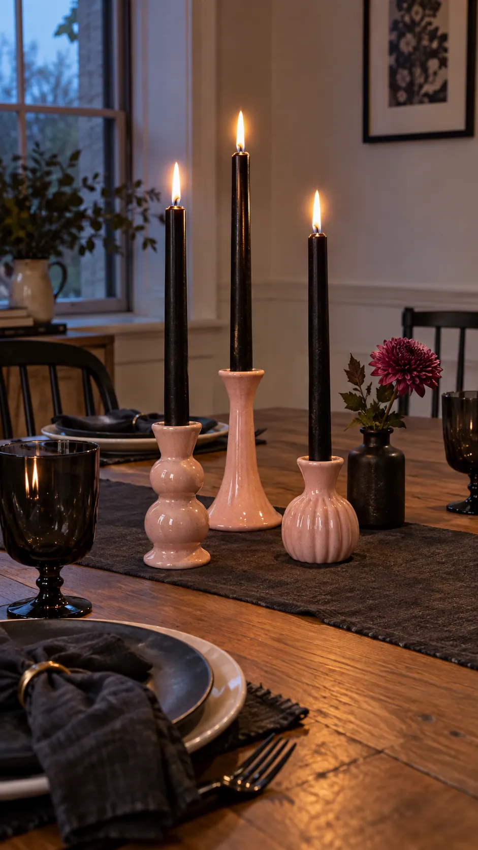 Pink and black Halloween decor with three black taper candles held by mismatched pale pink ceramic holders